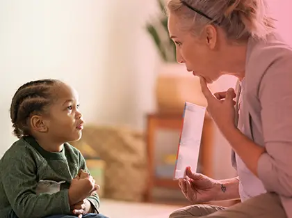 Therapist uses visual aids to guide a young child through a personalized ABA therapy session focused on communication skills.