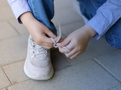 Child practices tying shoelaces as part of developing independent living skills during ABA therapy
