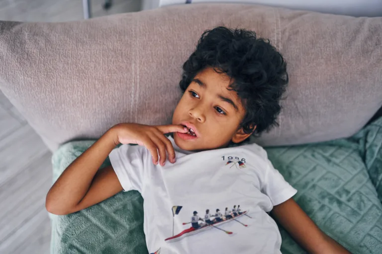Portrait of an attentive and serious boy on the sofa watching TV, front view
